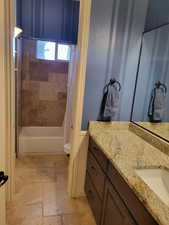 Full bath with vanity, shower / bath combination with curtain, and stone tile flooring