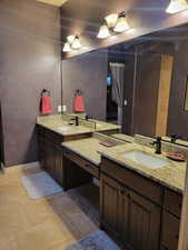 Full bath featuring double vanity and stone tile flooring
