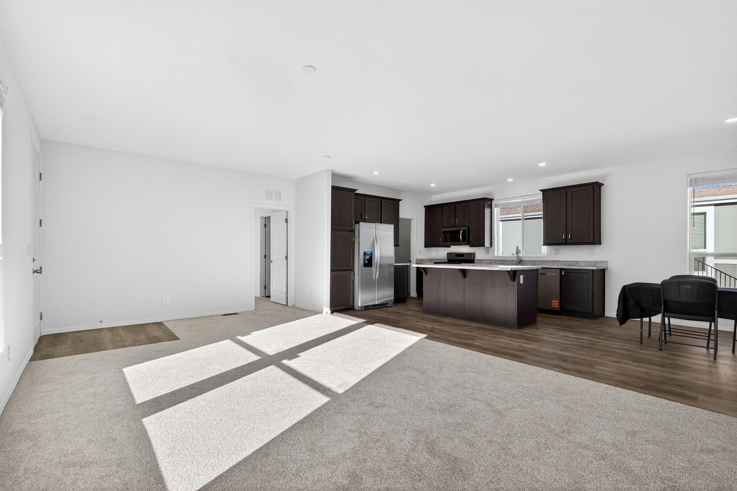Kitchen with light countertops, a breakfast bar, dark wood finish cabinetry, a kitchen island, and stainless steel appliances