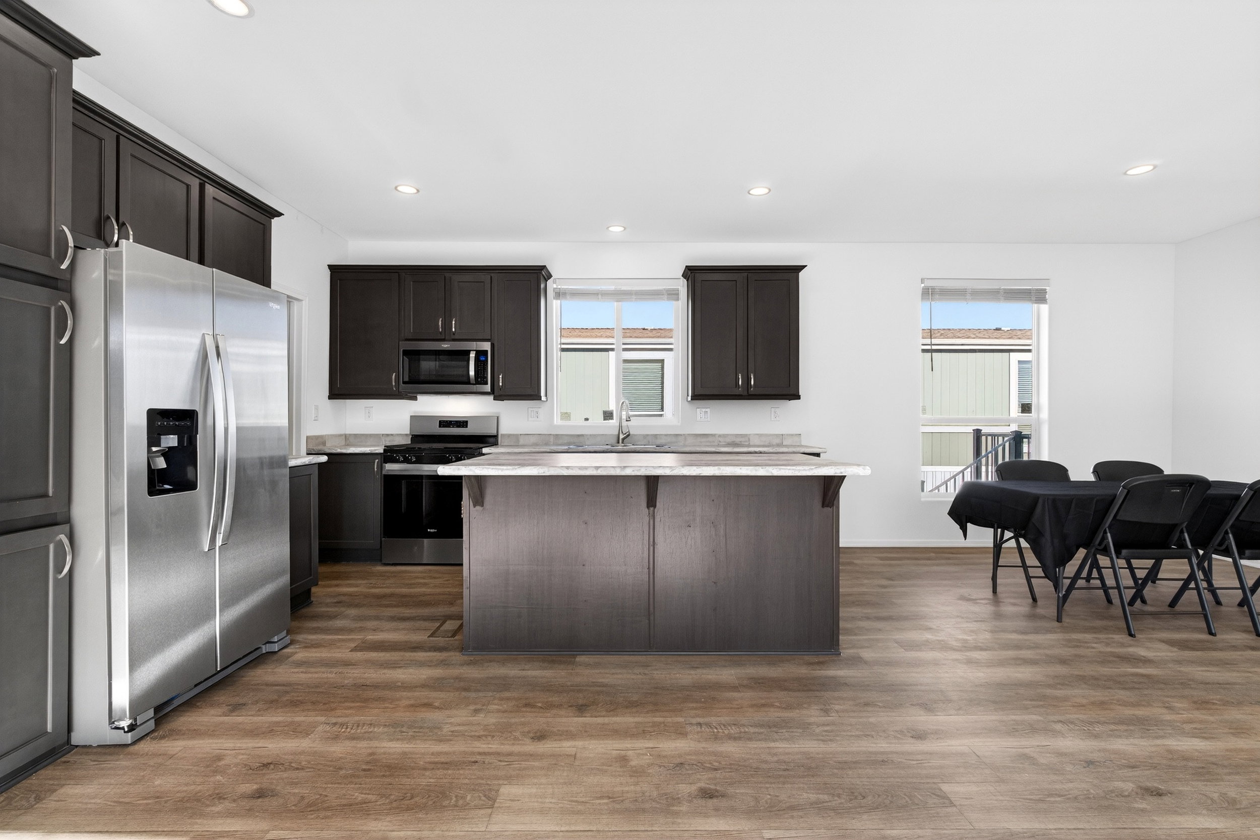 Kitchen featuring a breakfast bar area, stainless steel appliances, dark wood-style flooring, dark wood finish cabinets, and a kitchen island