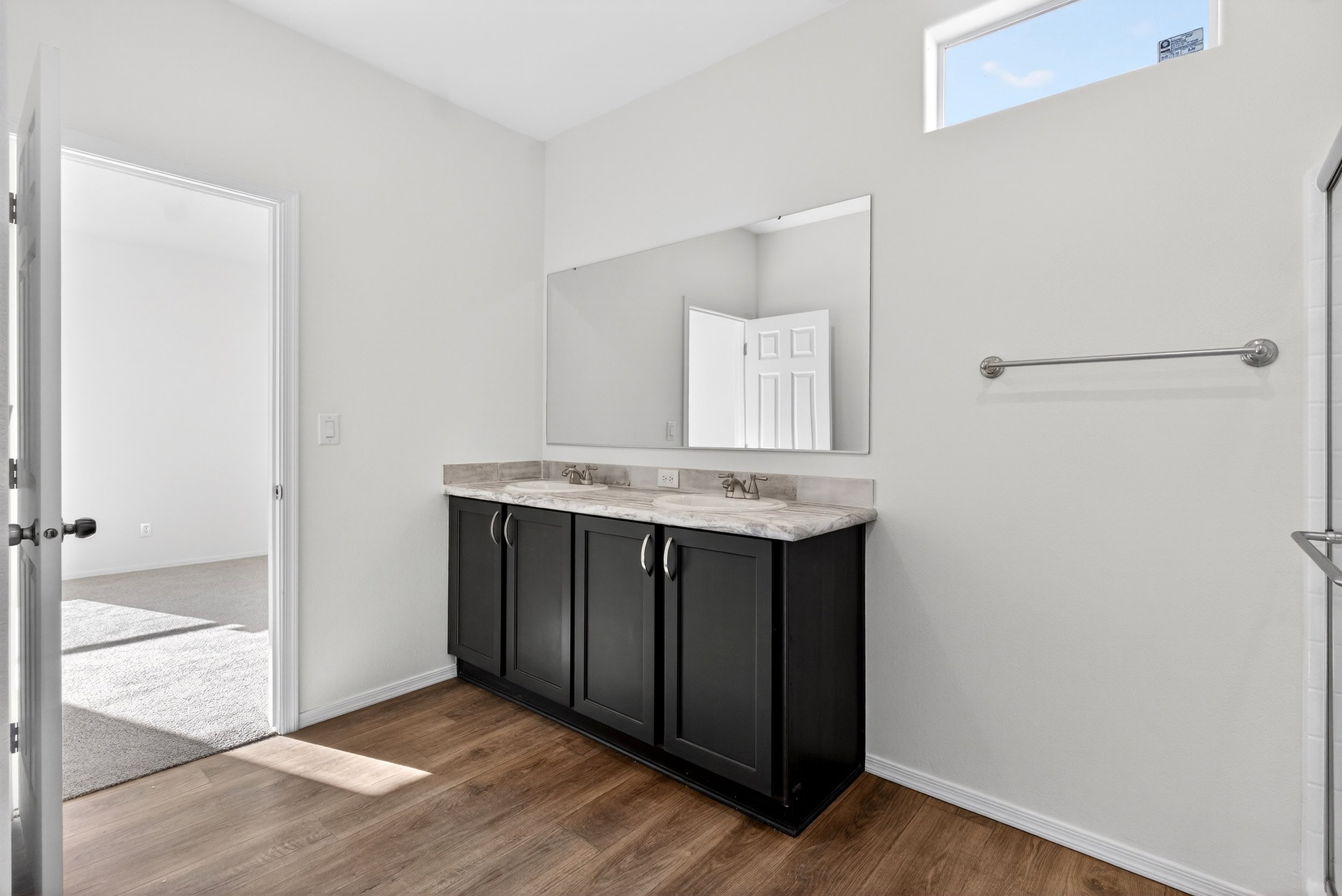Bathroom featuring double vanity and dark wood-style floors