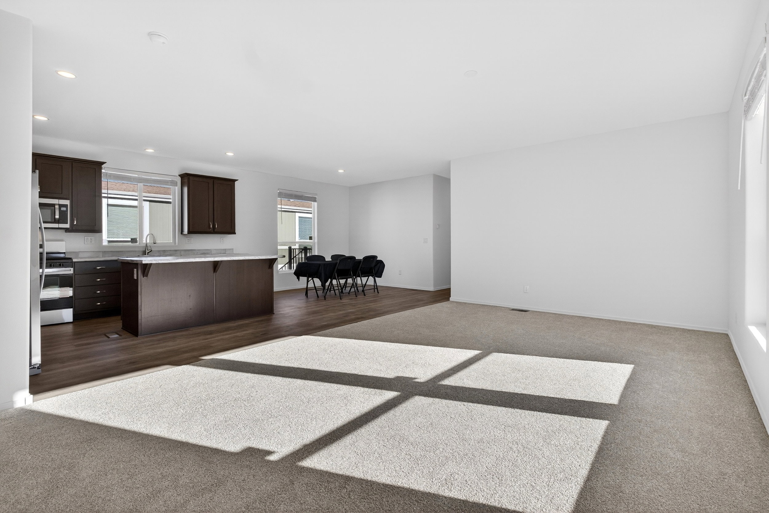 Living area with dark colored carpet and recessed lighting