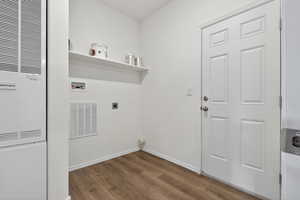 Laundry room with a heating unit, dark wood-type flooring, hookup for an electric dryer, and hookup for a washing machine