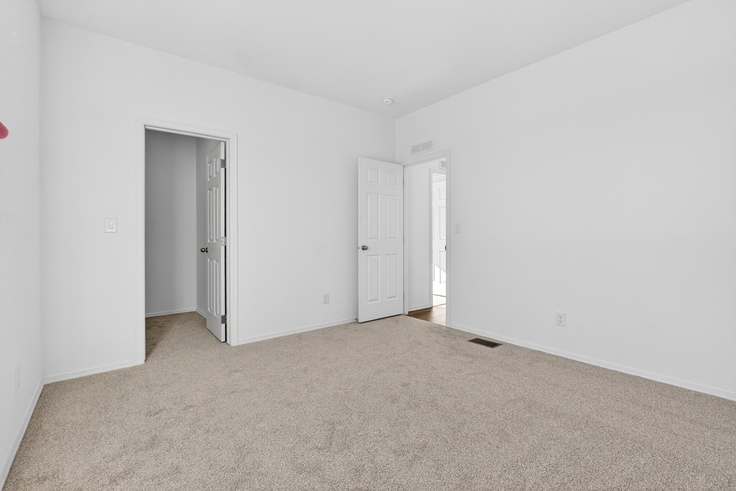 Unfurnished bedroom with light carpet and a spacious closet