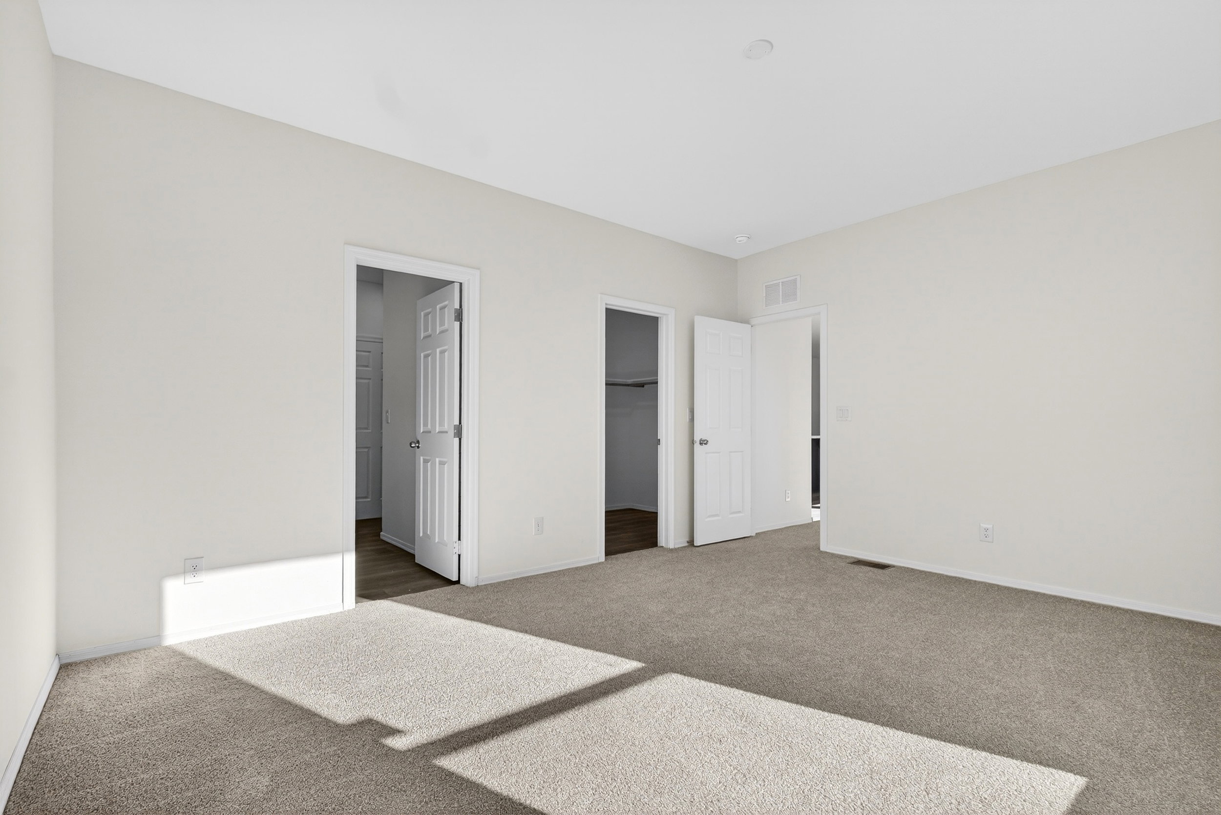 Unfurnished bedroom with a walk in closet, carpet floors, and ensuite bathroom