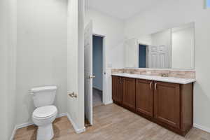 Full bath featuring double vanity and light wood-style flooring