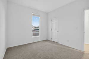 Unfurnished bedroom with light colored carpet and baseboards