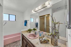Full bath with vanity, a shower stall, a garden tub, and a textured ceiling