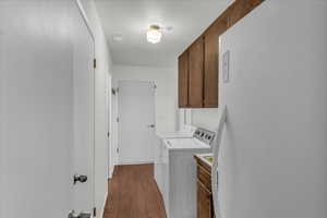 Laundry area featuring cabinet space, dark wood-type flooring, separate washer and dryer, and a textured ceiling