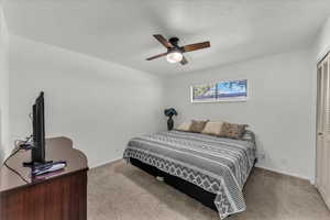 Bedroom featuring light carpet, a ceiling fan, and a textured ceiling