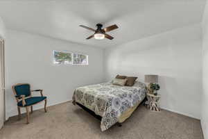 Carpeted bedroom with a textured ceiling and a ceiling fan