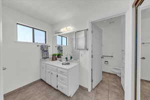 Bathroom with vanity, a textured ceiling, and light tile patterned flooring