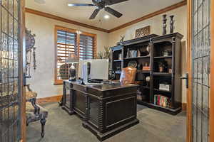 Home office featuring crown molding, carpet flooring, and a ceiling fan