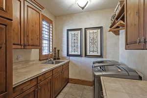Kitchen with tile countertops, washer and dryer, brown cabinets, and light tile patterned flooring