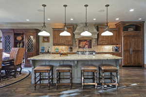 Kitchen with brown cabinets, decorative backsplash, a kitchen bar, and recessed lighting