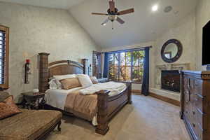 Bedroom with high vaulted ceiling, a premium fireplace, ceiling fan, a textured wall, and carpet flooring