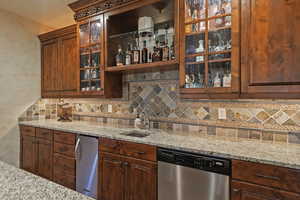 Kitchen with stainless steel appliances, backsplash, glass insert cabinets, light stone counters, and open shelves