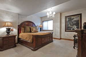 Bedroom featuring a textured ceiling, a chandelier, and light carpet