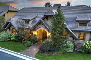 View of front facade with stone siding, stucco siding, and a lawn