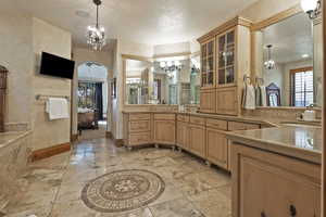 Full bath featuring a chandelier, vanity, healthy amount of natural light, and ensuite bathroom