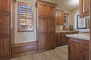 Kitchen featuring tile countertops, brown cabinetry, and light tile patterned floors