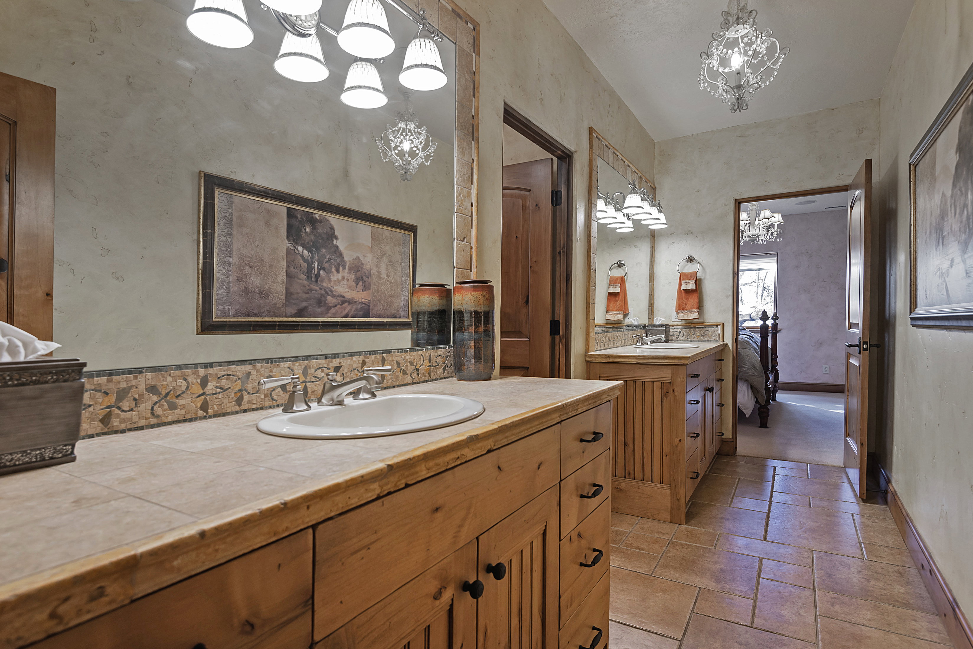 Bathroom featuring vanity, a chandelier, and stone tile floors