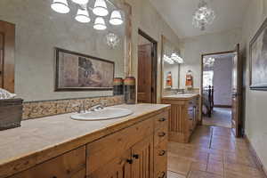 Bathroom featuring vanity, a chandelier, and stone tile floors