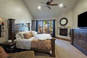 Bedroom with high vaulted ceiling, a premium fireplace, carpet, a ceiling fan, and a textured wall