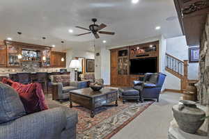 Carpeted living area with a ceiling fan, recessed lighting, bar, and stairs