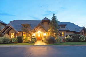 View of front of home featuring stucco siding, stone siding, and a yard