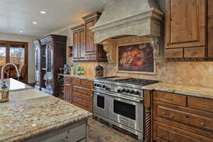 Kitchen with range with two ovens, light stone counters, dark wood-style flooring, decorative backsplash, and recessed lighting