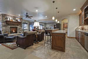 Living room with a ceiling fan, arched walkways, and a fireplace