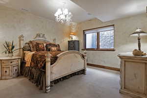 Bedroom featuring a chandelier, carpet flooring, and a textured wall