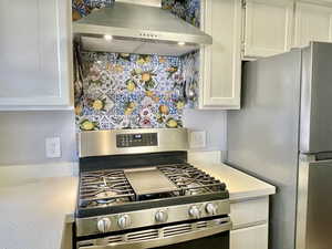 Kitchen featuring appliances with stainless steel finishes, light countertops, extractor fan, and white cabinetry