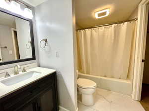 Bathroom with shower / bath combination with curtain, vanity, and light marble finish floors