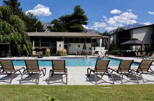 Community pool with a patio area, a mountain view, and a yard