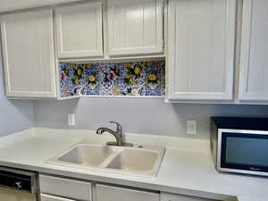Kitchen with light countertops, appliances with stainless steel finishes, and white cabinets
