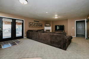 Living room featuring light colored carpet, a textured ceiling, and a fireplace
