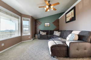 Carpeted living area featuring vaulted ceiling, a ceiling fan, a baseboard heating unit, and a textured ceiling