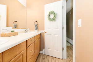 Full bathroom with double vanity and light wood-style flooring