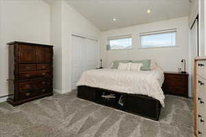 Bedroom featuring a closet, lofted ceiling, light colored carpet, and recessed lighting