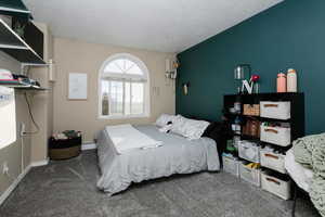 Bedroom with carpet floors, baseboard heating, and a textured ceiling