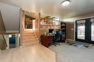 Office space featuring lofted ceiling, french doors, a textured ceiling, carpet, and wood finished floors