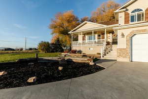 View of front of home with a porch, a garage, a front lawn, driveway, and stairs