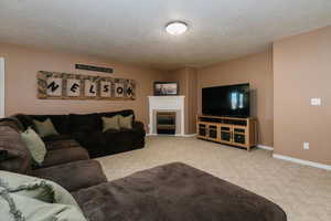 Carpeted living room featuring a textured ceiling and a fireplace