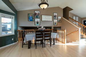 Dining room featuring light wood-style floors, lofted ceiling, and stairway