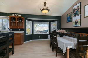 Dining room with healthy amount of natural light, light wood finished floors, and lofted ceiling