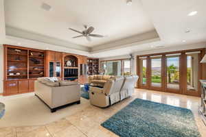 Living area featuring a raised ceiling, recessed lighting, ceiling fan, and light tile patterned flooring
