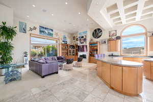 Kitchen featuring light stone countertops, a towering ceiling, recessed lighting, and open floor plan