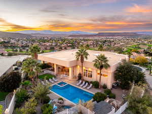 Back of property at dusk with a patio area, a mountain view, stucco siding, and a pool with connected hot tub